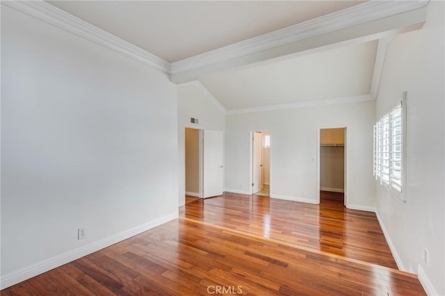 empty room with wood-type flooring, ornamental molding, and vaulted ceiling