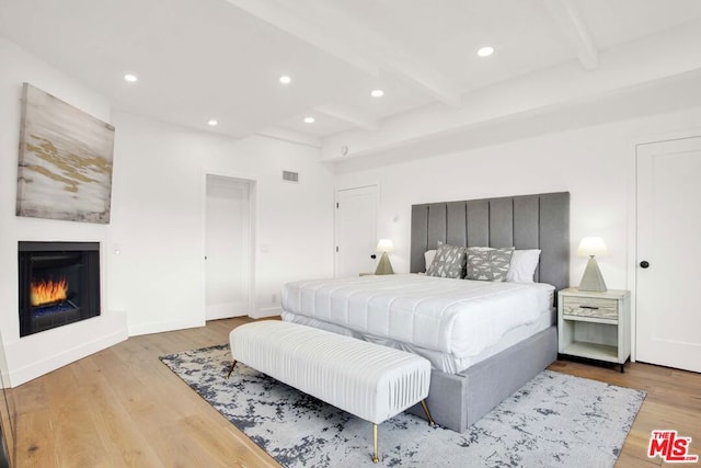 bedroom with beam ceiling and light wood-type flooring