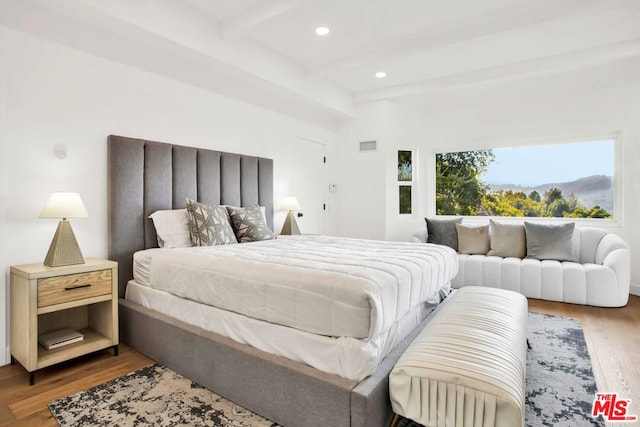 bedroom featuring hardwood / wood-style flooring and beamed ceiling