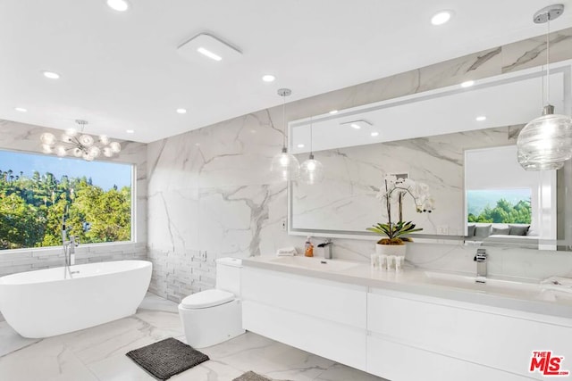 bathroom with tile walls, a chandelier, a bathtub, vanity, and toilet