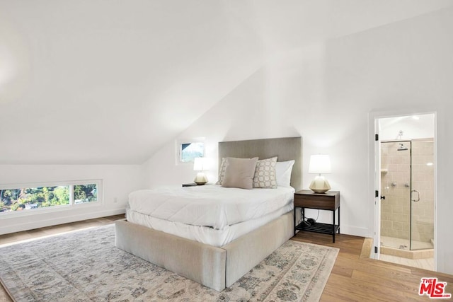 bedroom featuring ensuite bath, vaulted ceiling, and light wood-type flooring