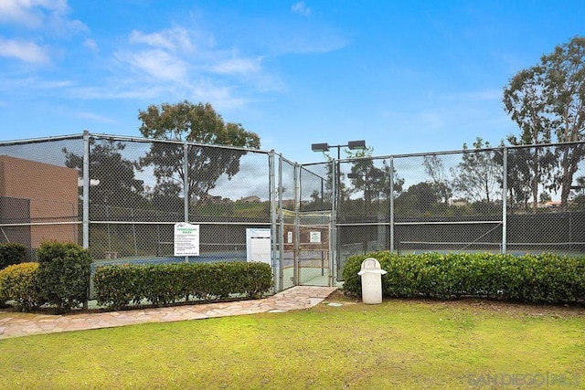 view of tennis court featuring a lawn