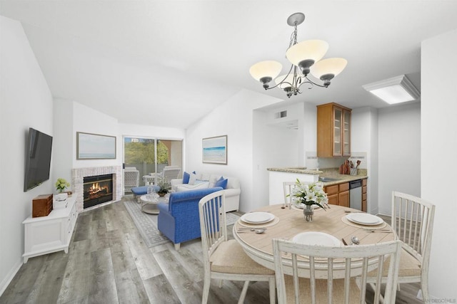 dining area with vaulted ceiling, a notable chandelier, and light wood-type flooring