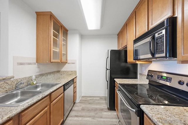 kitchen featuring sink, backsplash, light hardwood / wood-style floors, stainless steel appliances, and light stone countertops