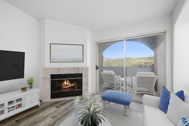 living room with a brick fireplace and hardwood / wood-style floors