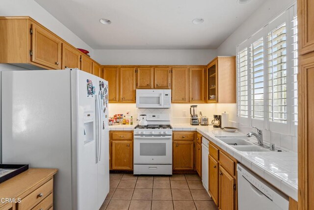 kitchen featuring sink, white appliances, light tile patterned floors, and a healthy amount of sunlight