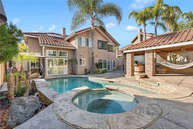 rear view of house featuring a swimming pool with hot tub and a patio area