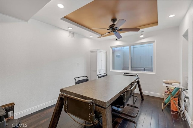 dining space with a tray ceiling, dark wood-type flooring, and ceiling fan