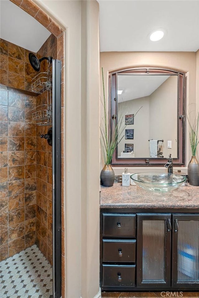 bathroom with a tile shower and vanity