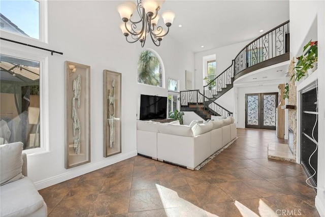 unfurnished living room featuring french doors, a towering ceiling, and a notable chandelier