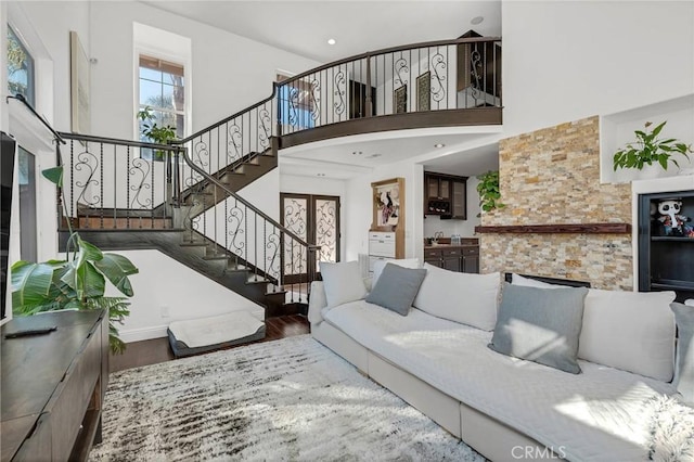 living room with a towering ceiling, hardwood / wood-style floors, and french doors