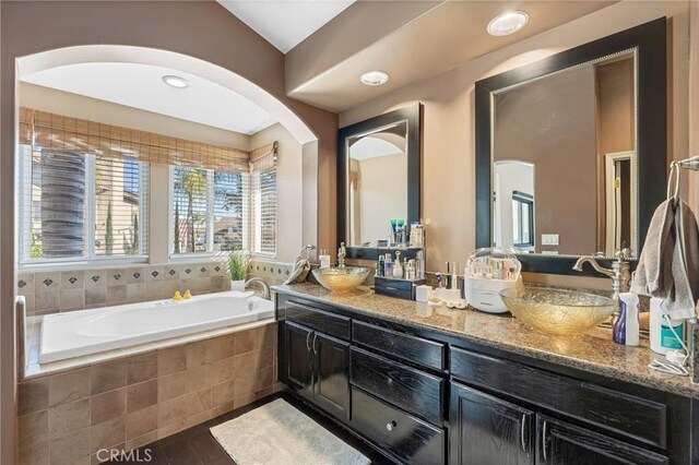 bathroom featuring vanity and tiled bath