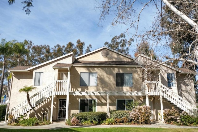 view of front facade with stairs and stucco siding