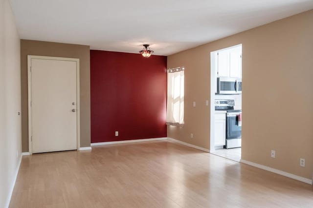 spare room with light wood-type flooring and baseboards