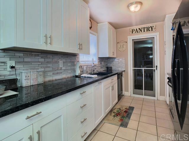 kitchen with white cabinetry, light tile patterned floors, decorative backsplash, and dark stone counters