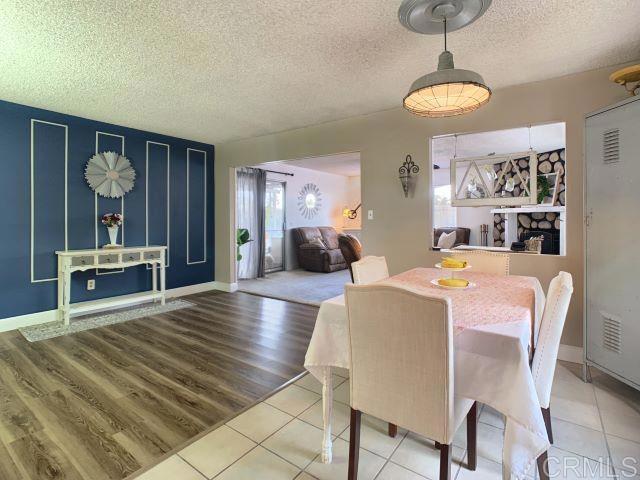 dining space with wood-type flooring, a healthy amount of sunlight, and a textured ceiling