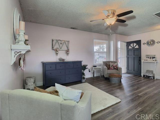 living room with ceiling fan, dark hardwood / wood-style floors, and a textured ceiling