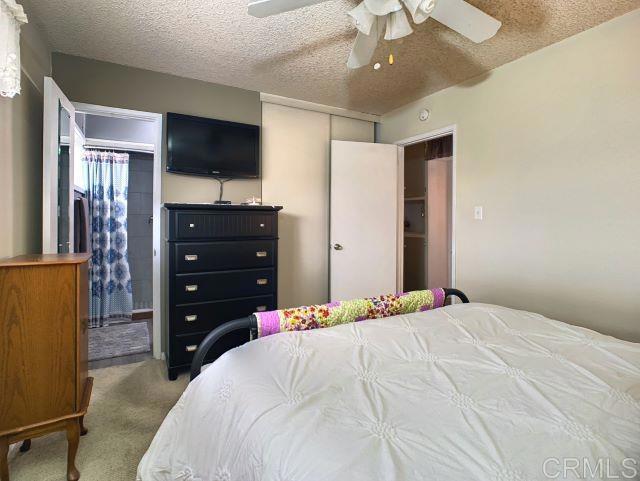 carpeted bedroom featuring ceiling fan and a textured ceiling