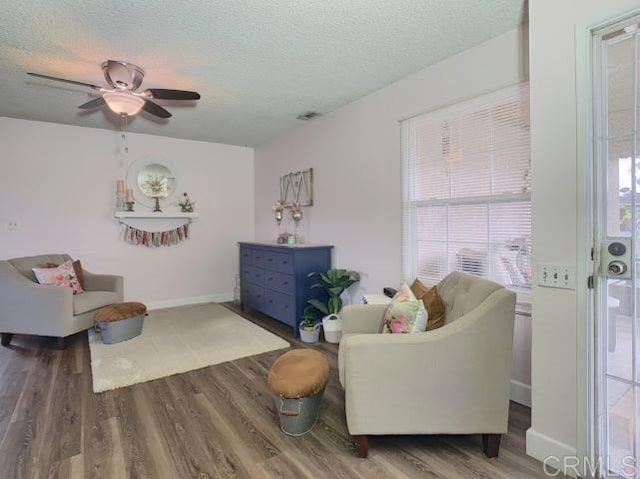 living room featuring hardwood / wood-style floors, a textured ceiling, and ceiling fan