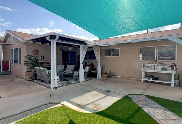 back of house with a patio, outdoor lounge area, a ceiling fan, and stucco siding