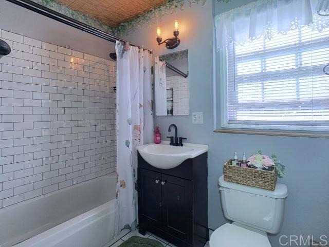 full bathroom featuring toilet, shower / bathtub combination with curtain, and vanity