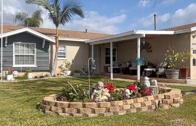 back of property with a lawn and stucco siding