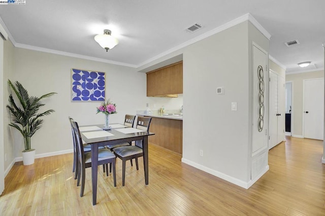 dining area with ornamental molding and light hardwood / wood-style flooring