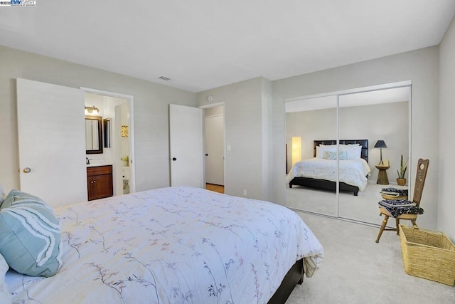 carpeted bedroom with a closet and ensuite bathroom