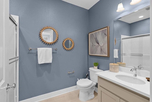 bathroom featuring vanity, a shower with shower door, and toilet