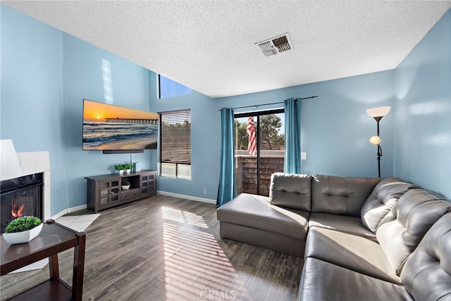 living room with a tiled fireplace, hardwood / wood-style floors, and a textured ceiling