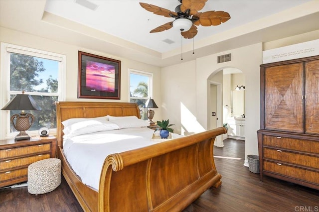 bedroom with dark hardwood / wood-style flooring, a tray ceiling, and ceiling fan