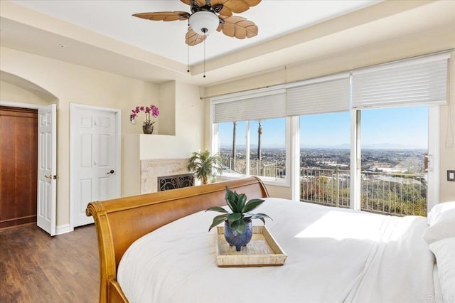 bedroom with a raised ceiling, ceiling fan, and dark hardwood / wood-style flooring