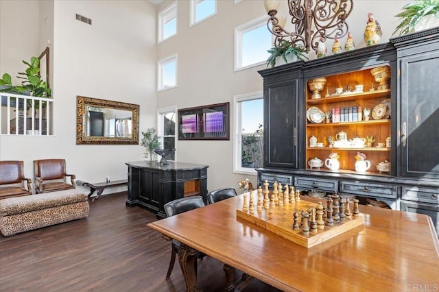 dining area with dark hardwood / wood-style flooring, a towering ceiling, and a chandelier