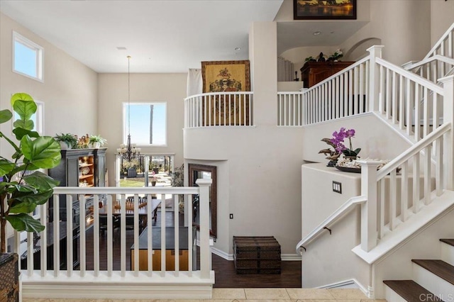 stairs featuring tile patterned flooring, a towering ceiling, and an inviting chandelier