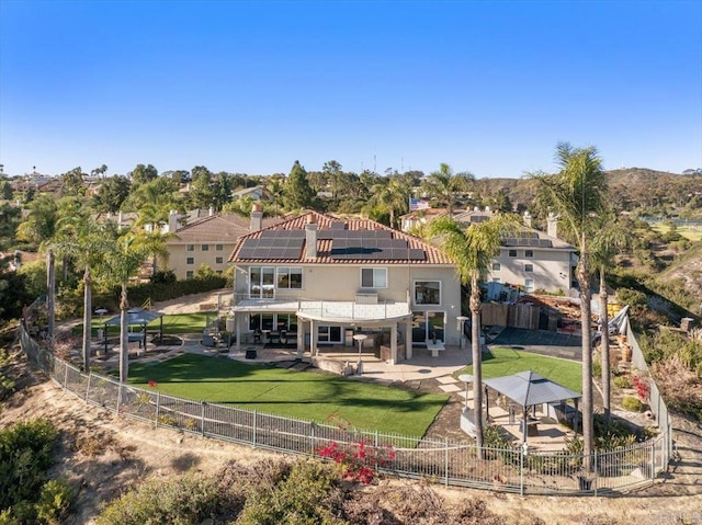 back of property with a gazebo, a lawn, and solar panels