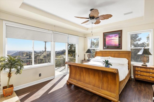 bedroom featuring dark hardwood / wood-style flooring, a tray ceiling, access to outside, and ceiling fan