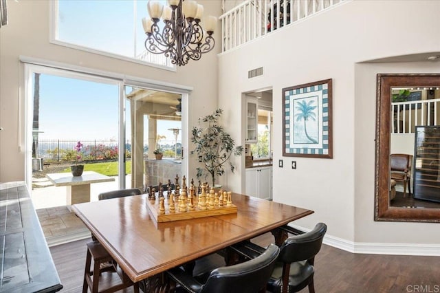 dining area with a high ceiling, dark wood-type flooring, and a chandelier