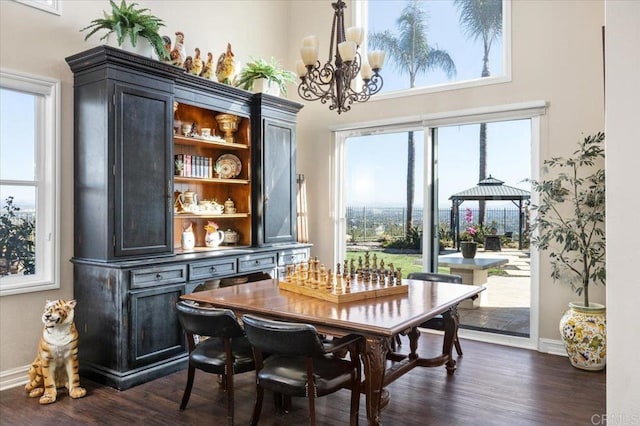 dining area with a high ceiling, an inviting chandelier, and dark hardwood / wood-style flooring