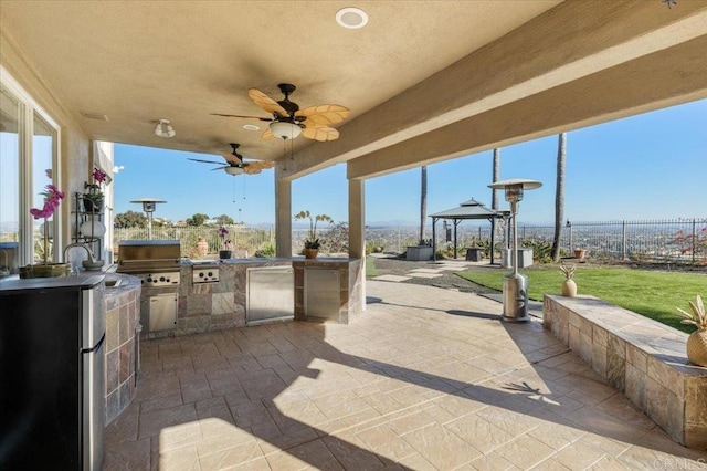 view of patio featuring a gazebo, area for grilling, ceiling fan, and grilling area