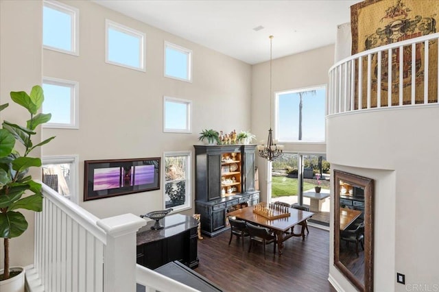 living room with dark hardwood / wood-style floors, an inviting chandelier, and a towering ceiling