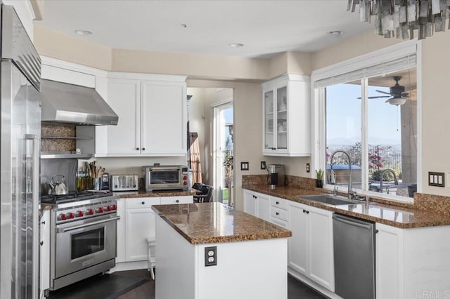 kitchen with a kitchen island, appliances with stainless steel finishes, white cabinets, and wall chimney exhaust hood