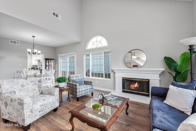 living room featuring dark wood-type flooring, an inviting chandelier, and a high ceiling