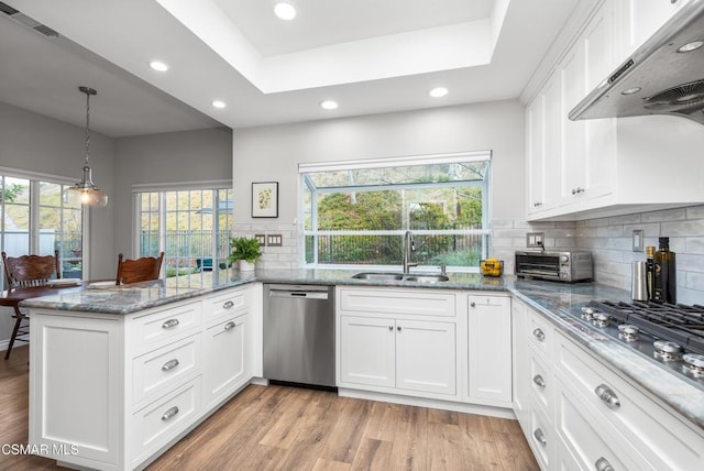 kitchen featuring white cabinetry, sink, range hood, and appliances with stainless steel finishes