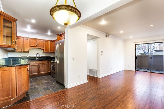 kitchen featuring dark wood-type flooring, sink, crown molding, dark stone countertops, and stainless steel fridge