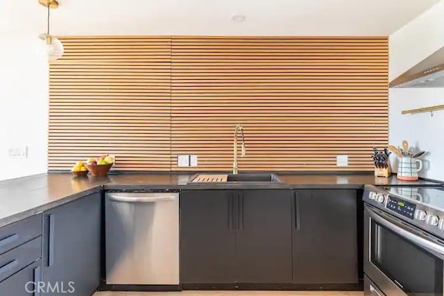 kitchen featuring sink, decorative light fixtures, stainless steel appliances, and wall chimney exhaust hood