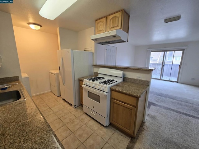 kitchen featuring light brown cabinetry, sink, light carpet, washer and dryer, and white appliances