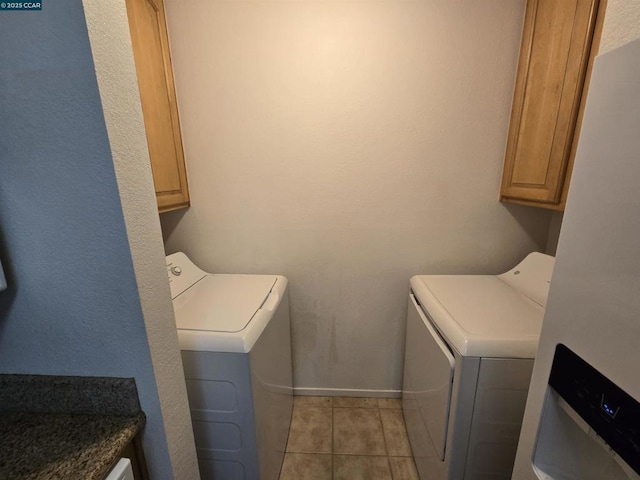 clothes washing area with light tile patterned flooring, cabinets, and washer and clothes dryer