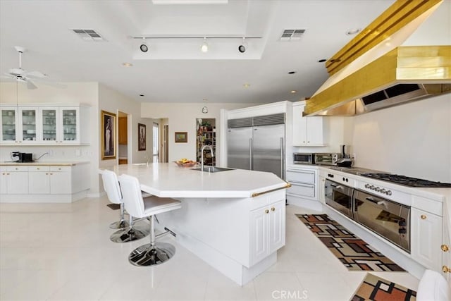 kitchen featuring a breakfast bar area, white cabinetry, light tile patterned floors, stainless steel appliances, and a kitchen island with sink