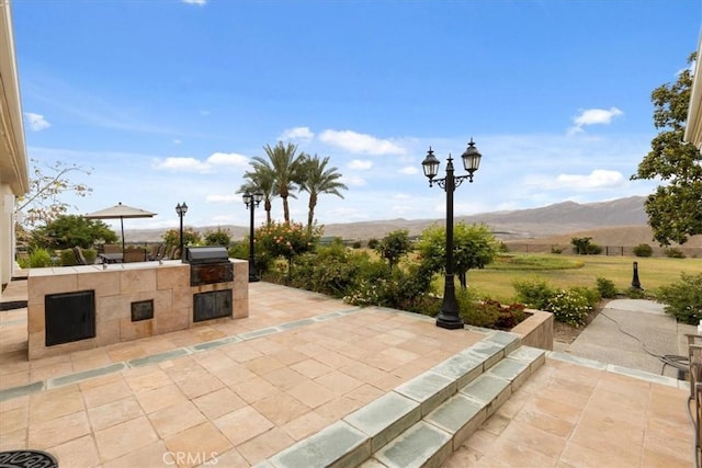 view of patio featuring an outdoor kitchen, a mountain view, and area for grilling