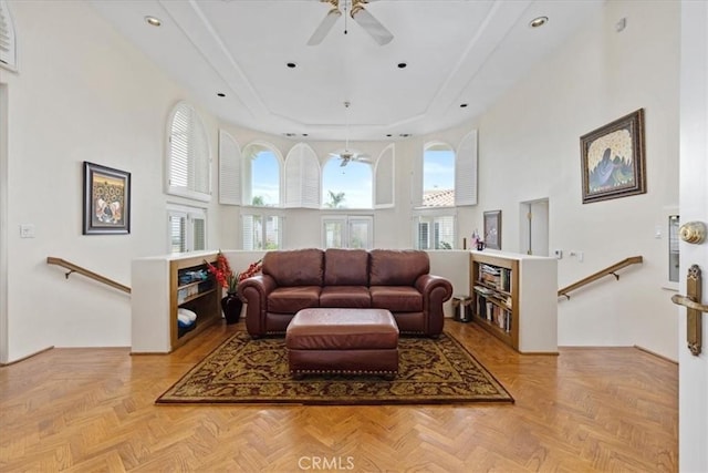 living room with light parquet flooring, a tray ceiling, and a high ceiling